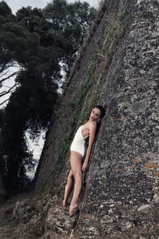 portrait of a beautiful young ballerina posing in front of a big wall of an old castle