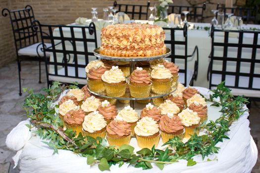 wedding cake on a table with small  cupcakes 