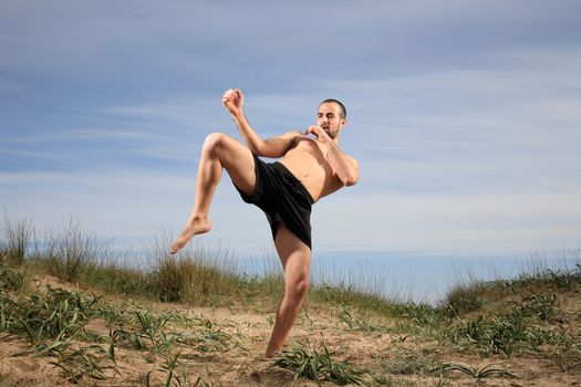 young martial arts instructor exercising on a sand hill