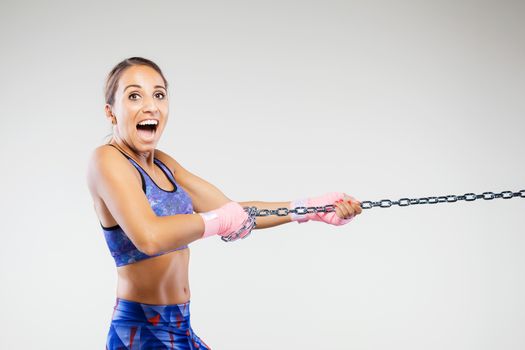 girl kickboxer pulling a chain with pink hand wraps