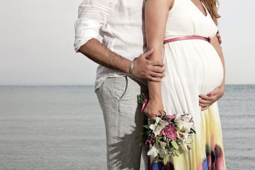 close up of man and  pregnant woman holding a flower bouquet