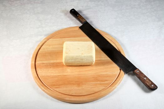 block of spicy cheese with a big knife on wooden plate