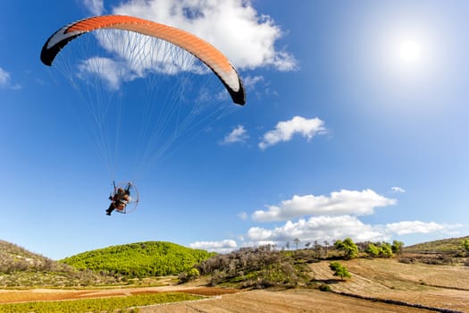 paraglider on field with hills and trees on a sunny day