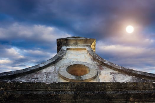 top of an old church against the blue cloudy sky with sun