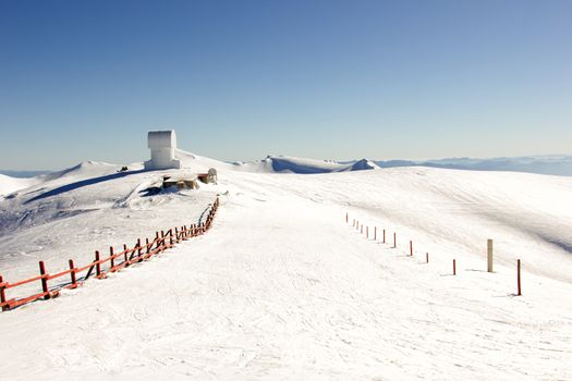 small observatory on the top of a mountain with snow