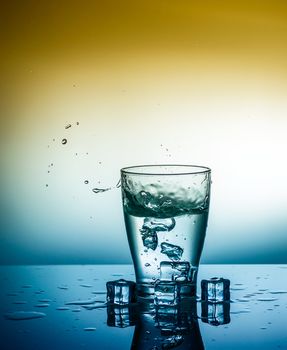 a glass of fresh clean water with falling ice cubes