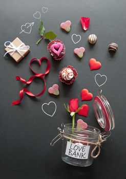 Hearts, cupcakes, roses and gifts pouring out of a love bank jar on a chalkboard