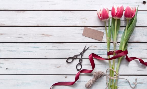 Pink tulips on a wooden background wtih gift tag