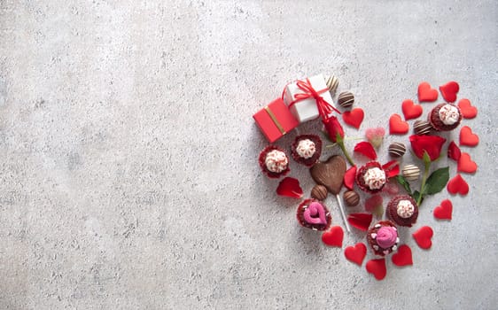Heart shape consisting of chocolates, cupcakes, flowers and gifts 