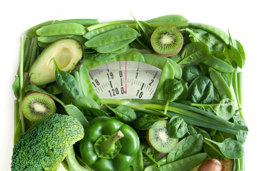 Green fruits and vegetables in the shape of bathroom weighing scales over a white background