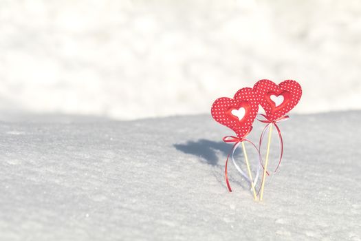 Beautiful valentine holiday background with two checkered hearts on cane, white snow surface.