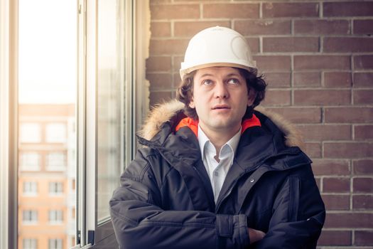 Man builder. Builder in protective clothing and helmet. Male builder. Portrait of mechanical worker. Engineer looking up. Copy space. Soft focus, toned