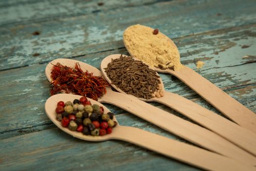 Saffron, pepper, cumin and mustard in a wooden spoons