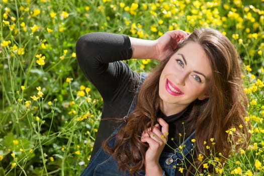 portrait of a beautiful young girl among yellow flowers in the nature