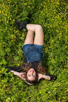 portrait of a beautiful young girl with headphones among yellow flowers of a garden