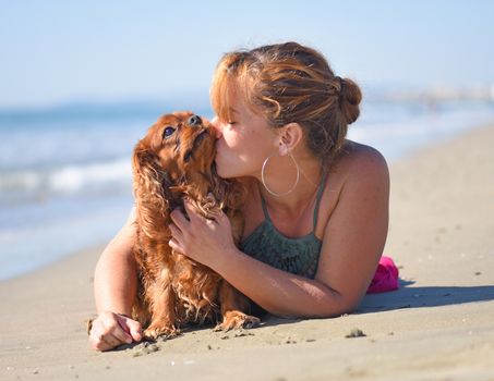 woman and dog kissing on the beach