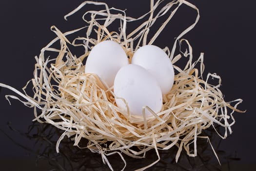 Three chicken eggs in the nest like On a black background