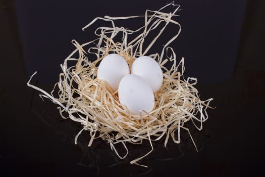 Three chicken eggs in the nest like On a black background