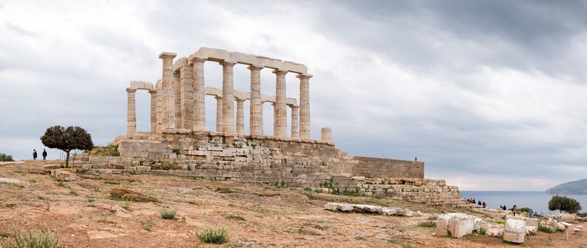 Ruins of an ancient Greek temple of Poseidon under dramatic cloudy sky, Cape Sounion, Greece