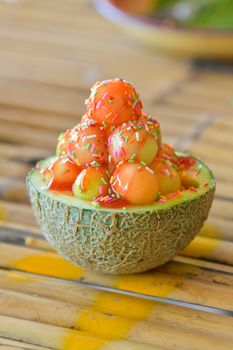 Ice cream cantaloupe with topping in cantaloupe.