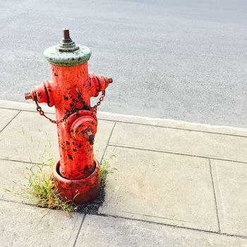 Red fire hydrant on a sidewalk of an urban street.