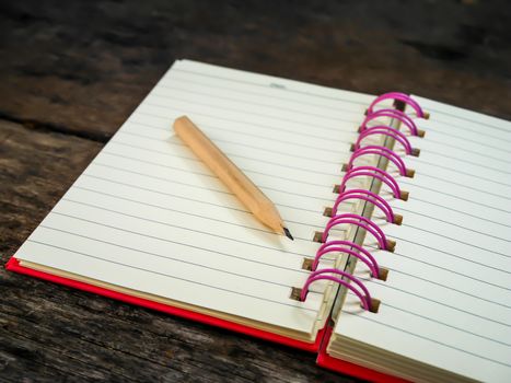 Note book with pencil on wooden table with selective focus