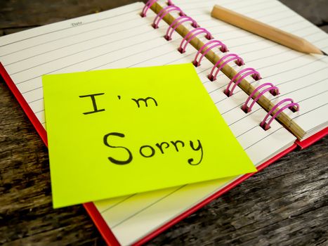Sorry paper note in note book on wooden table with selective focus