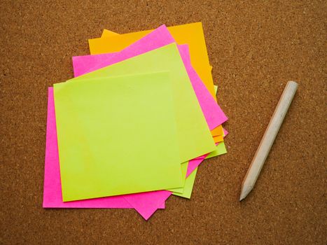 Many and colorful post note attach on wood board with wooden pencil