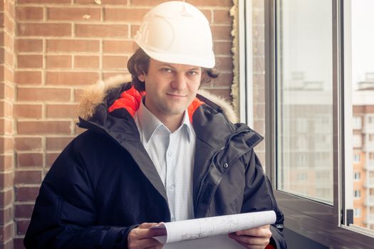 Portrait of an architect builder studying layout plan of the rooms, engineer working with documents on construction site, building and home renovation, professional foreman at work. Soft focus, toned