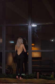 Blonde girl on the windowsill outside the window at night home cozy