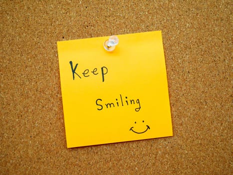 Keep smiling in post note on wooden board 