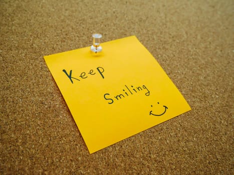 Keep smiling in post note on wooden board