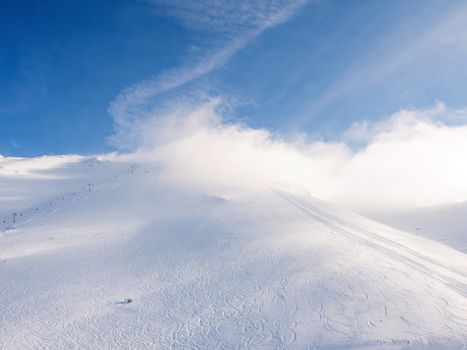 Clouds cover the lifts on top of the mountain in Kalavrita ski resort in a sunny day