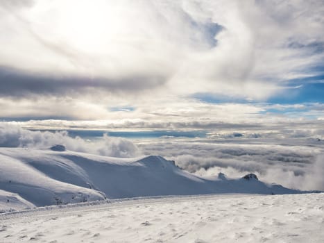 The top of the mountain Helmos in Kalavrita ski resort with snow and clouds in a sunny day