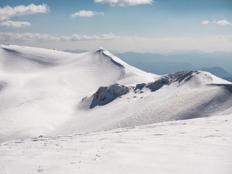 The top of the mountain Helmos in Kalavrita ski resort with snow and clouds in a sunny day