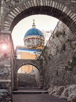 Traditional street with steps in Syros island with a church in the background