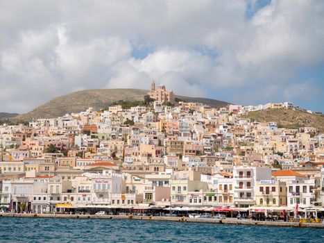 SYROS, GREECE - APRIL 10, 2016: View of Syros port with beautiful buildings and houses in a sunny day with clouds