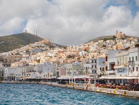 SYROS, GREECE - APRIL 10, 2016: View of Syros port with beautiful buildings and houses in a sunny day with clouds