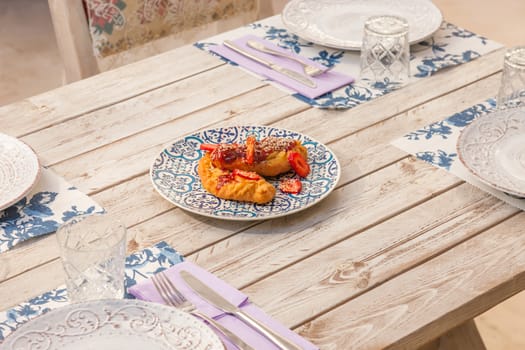 Gourmet greek cheese pie with tomato marmelade and strawberries served on a plate with pattern