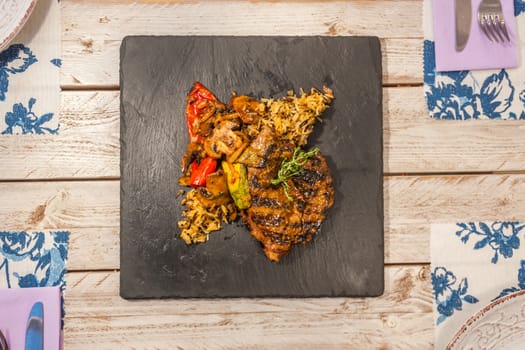 Grilled steak served with rice and vegetables on a graphite plate