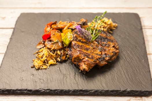 Grilled steak served with rice and vegetables on a graphite plate