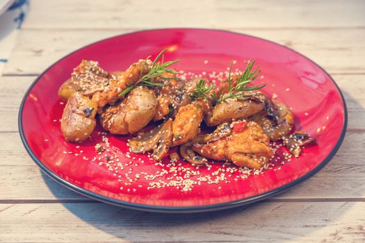 Chicken filet in sauce with smashed potatoes served on a red plate