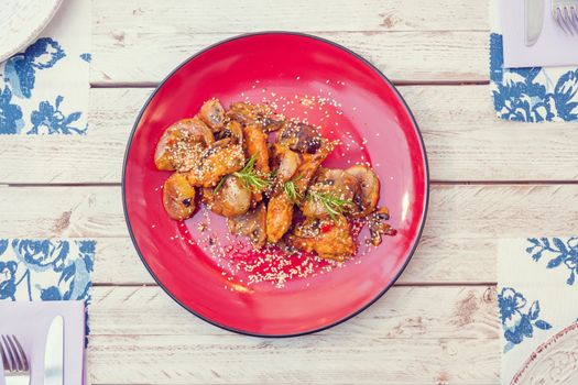 Chicken filet in sauce with smashed potatoes served on a red plate