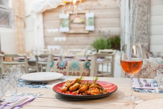 Chicken filet in sauce with smashed potatoes served on a table with a glass of wine