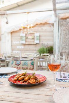 Chicken filet in sauce with smashed potatoes served on a table with a glass of wine