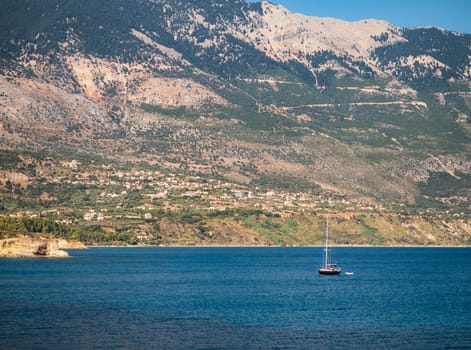 Small sail boat in the sea and a village in the background  in Kefalonia island,Greece