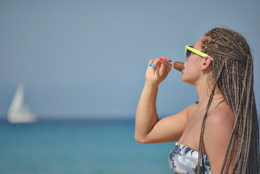 A beautiful girl in her 30ies eating ice cream by the sea or ocean.