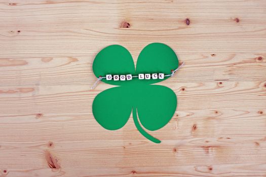 The words Good Luck and a cloverleaf on a cord on wood