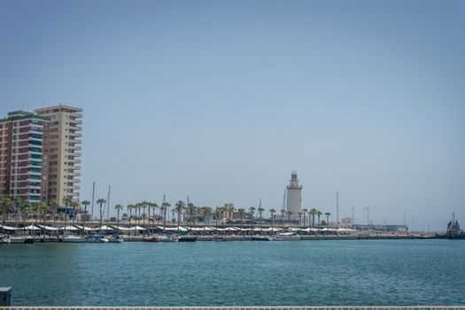 View of the lighthouse against the sea with palm trees at Malaga, Spain, Europe on a bright summer day