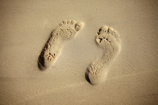 Pair prints of female legs on sand
